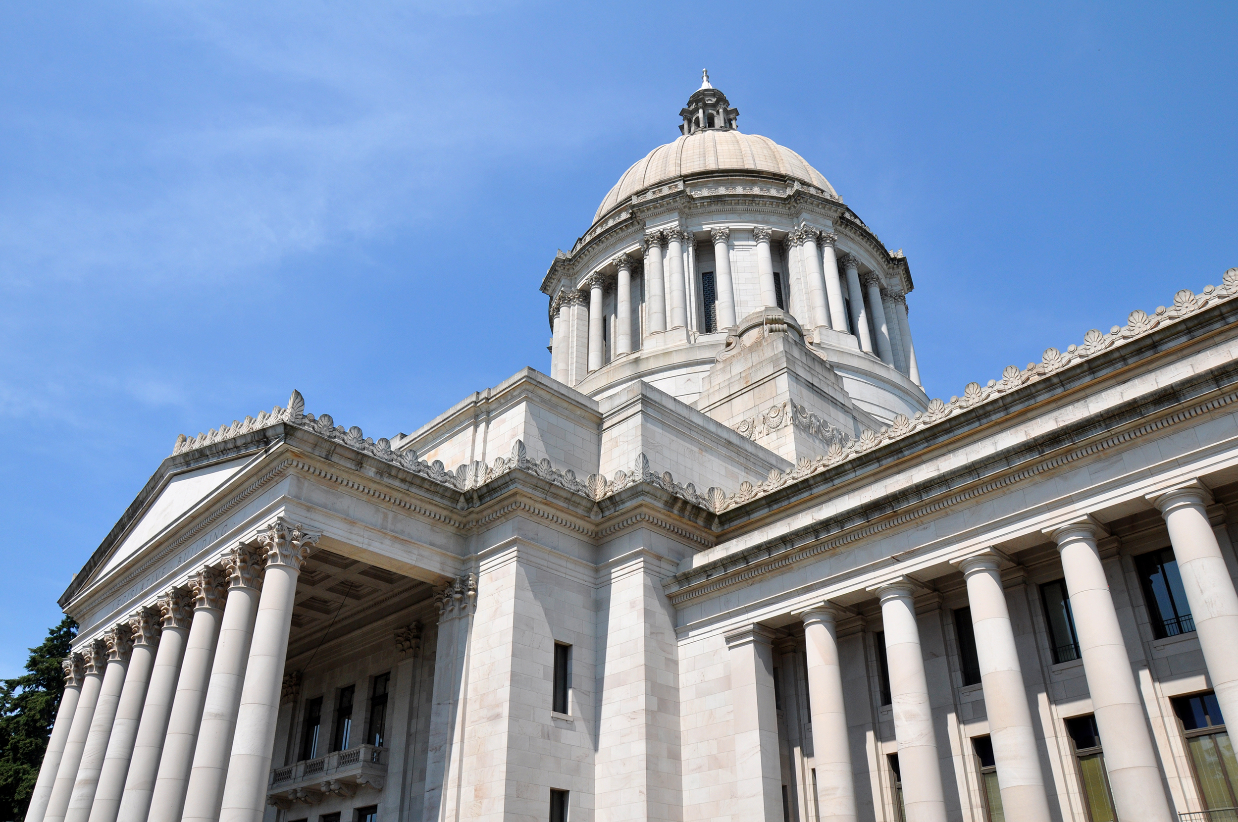 A photo of the Capitol of Olympia, Washington, taken at an upwards angle with a blue sky in the background